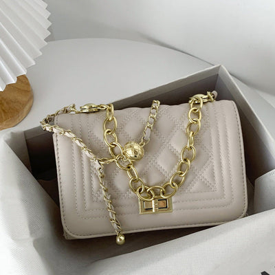 Beige handbag with gold chain in a box on a white background